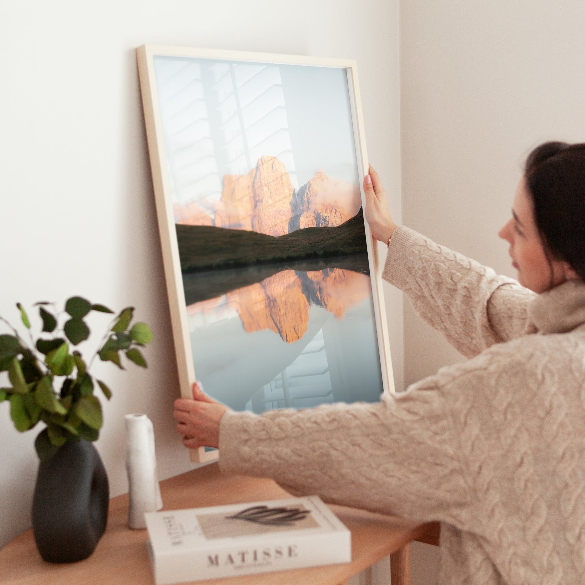 Woman placing Dolomites landscape print on wooden table